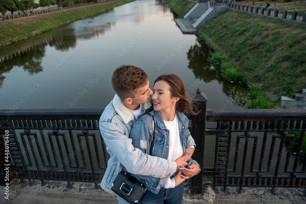 Happy couple embraces on the bridge. Guy hugs and kisses his beloved on river background. Above view. Romantic date