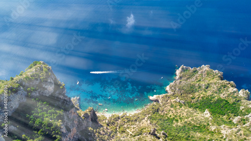 Speedboat speeding up along Capri coastline on a beautiful summer morning, Italy