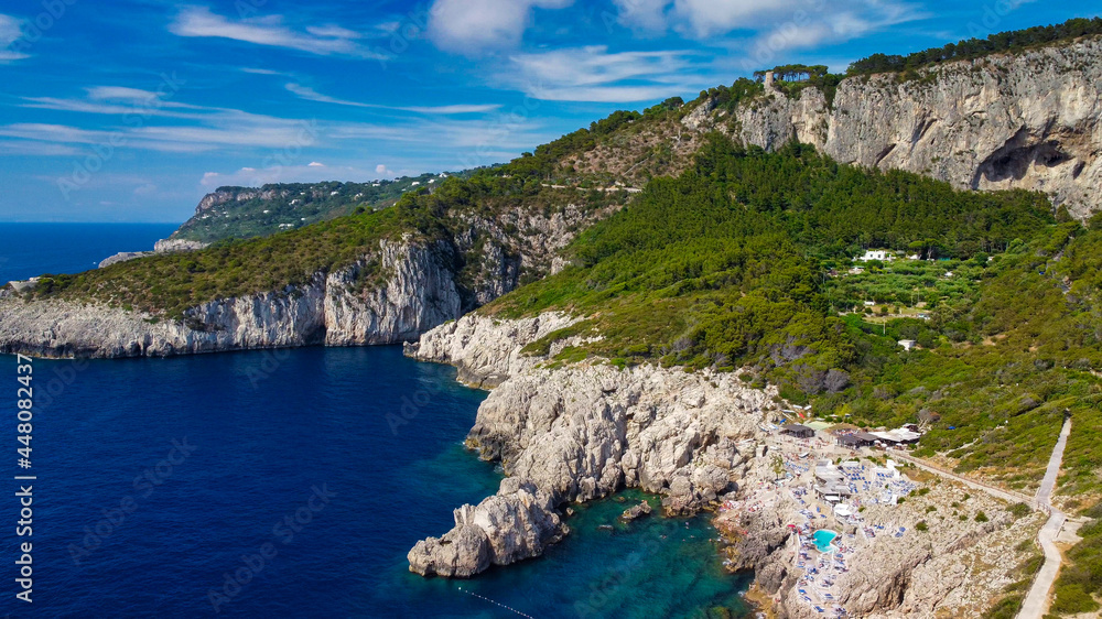Lighthouse and Beach of Capri in summer season. View from a moving drone.