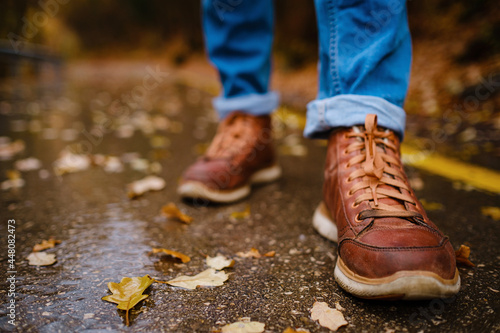 feet of a woman walking along asphalt road in autumn forest © YURII Seleznov