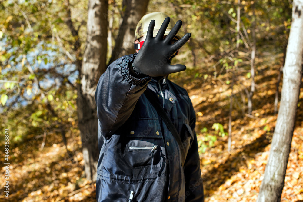 A man wearing a respirator mask and protective gloves in the forest at COVID-19 period.