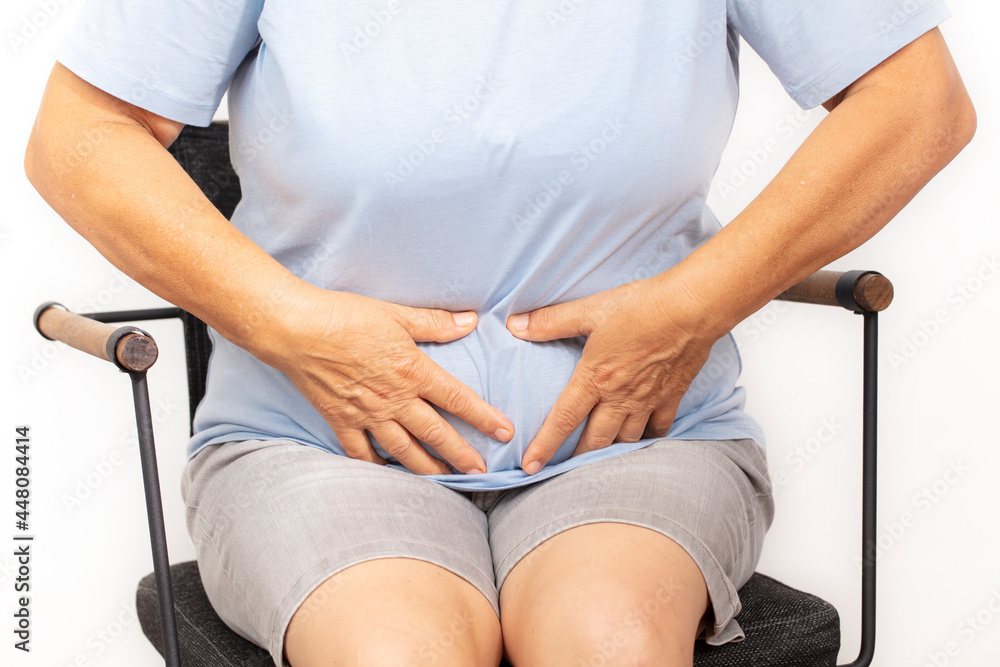 Unrecognizable female is holding her belly with her two hands because of abdominal pain. Unrecognizable female is holding her belly with her two hands because of abdominal pain.