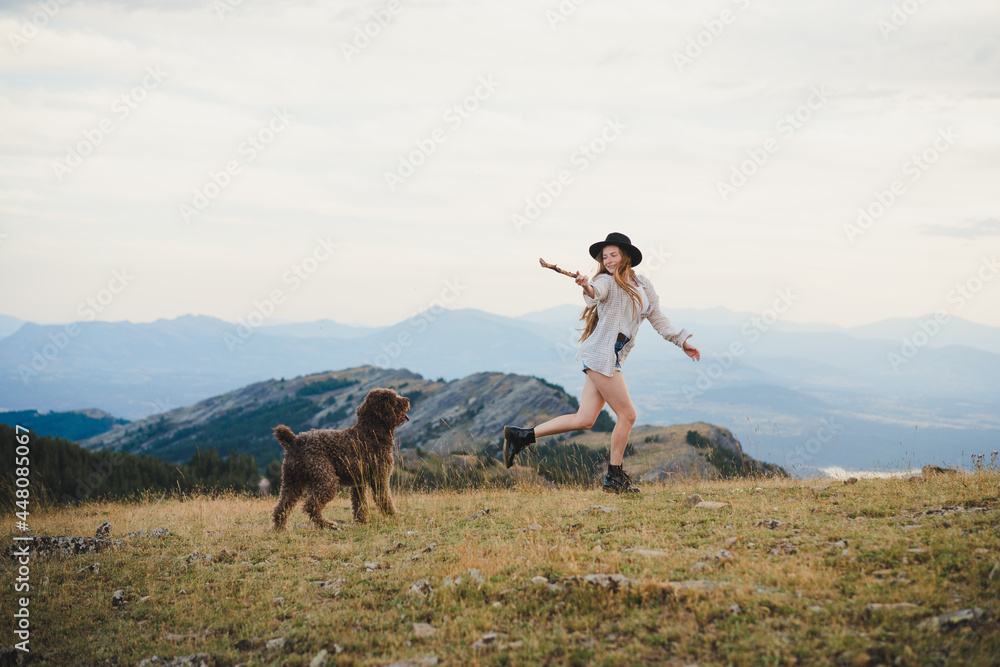 Cheerful woman playing with dog on hill in mountains Cheerful woman playing with dog on hill in mountains
