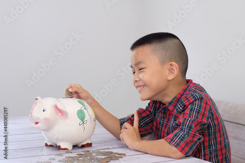 Boy coining Happily put in a piggy Bank It is a way for children to know how to save and save money. for the future of children concept of saving money