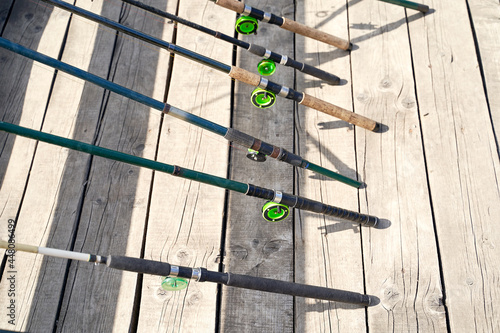 Obraz na płótnie Many fishing rods on the wooden pier by the river or lake on a sunny day w salonie