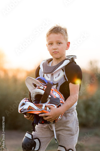 Fototapeta Naklejka Na Ścianę i Meble -  Child rider on motorcycle. Small biker dressed in a protective suit and helmet. The kid is engaged in motocross