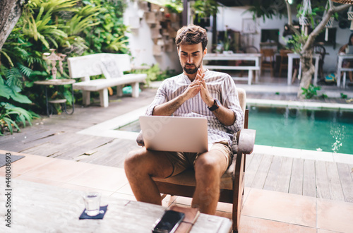 Pensive bearded man with laptop thinking about business project