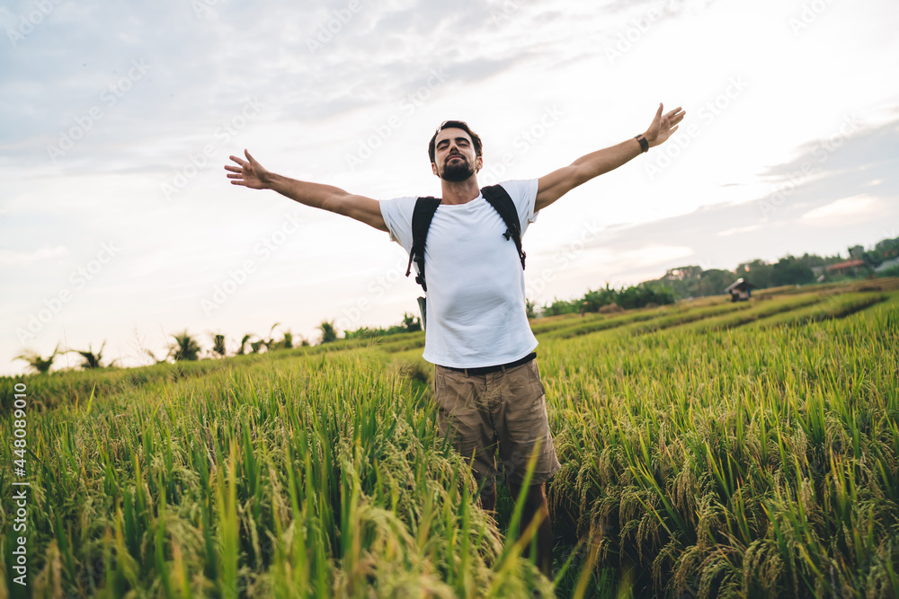 Serene man hiker spreading arms on green meadow Serene man hiker spreading arms on green meadow