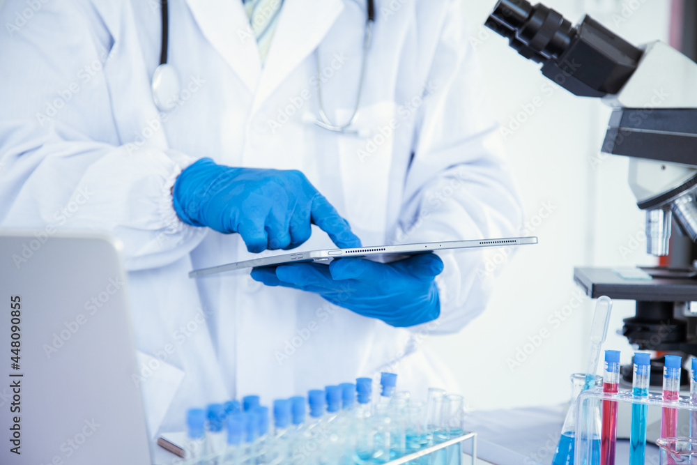 medical or scientific researcher researching and experimenting Multi-colored solution, vial and microscope In the laboratory or in the laboratory by wearing blue gloves and white clothing completely. medical or scientific researcher researching and experimenting Multi-colored solution, vial and microscope In the laboratory or in the laboratory by wearing blue gloves and white clothing completely.