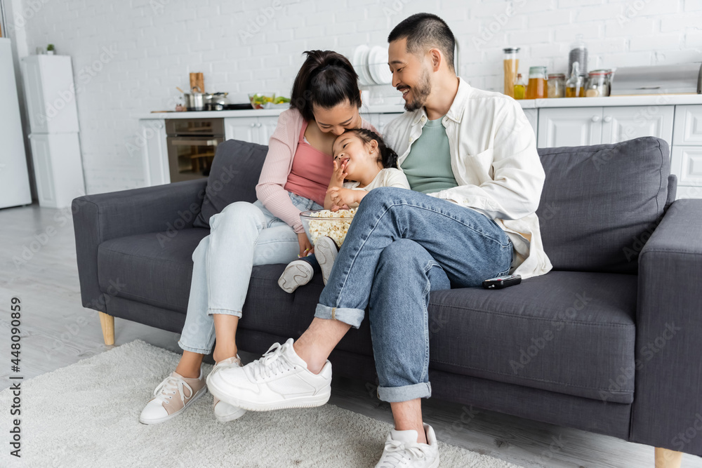 happy asian family watching movie near popcorn in living room