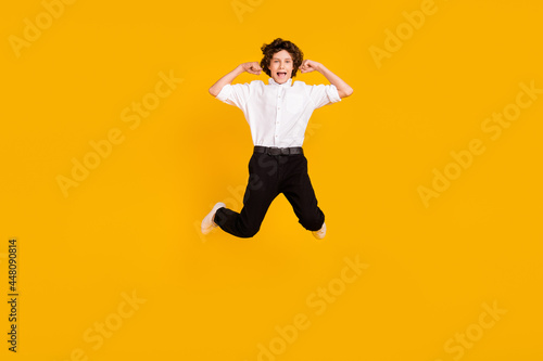 Fototapeta Naklejka Na Ścianę i Meble -  Full length photo of impressed small brunet boy jump wear uniform shoes isolated on yellow color background