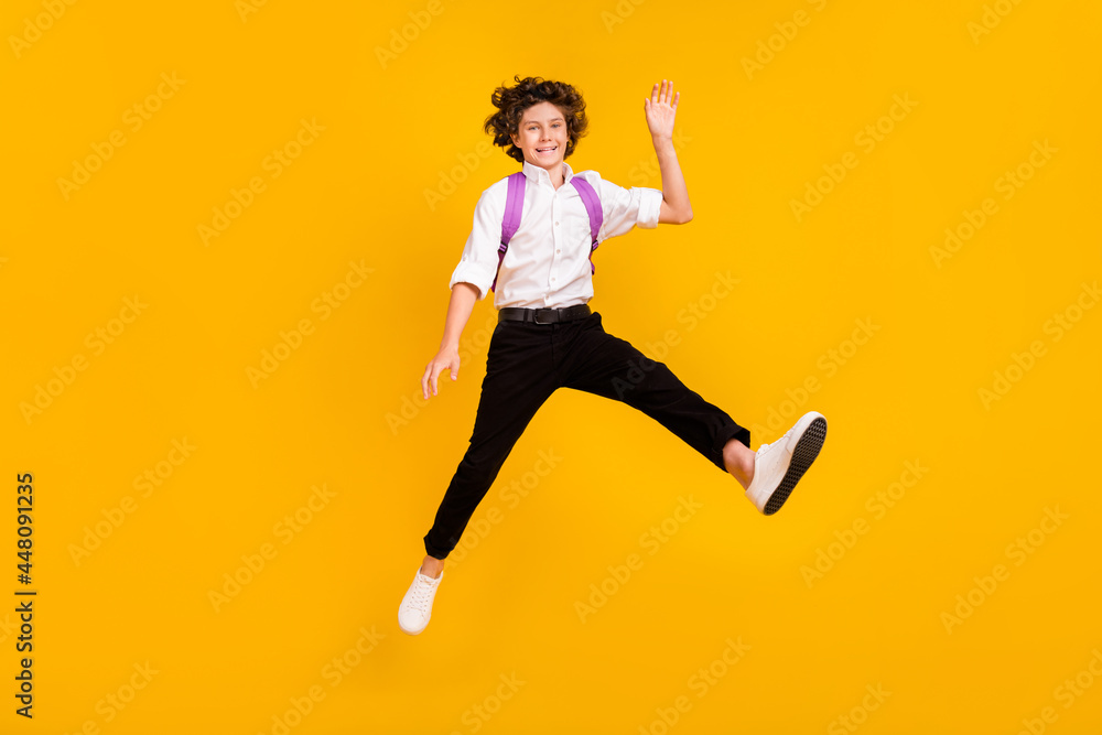 Photo of pretty friendly school boy wear white shirt rucksack smiling waving arm hi isolated yellow color background