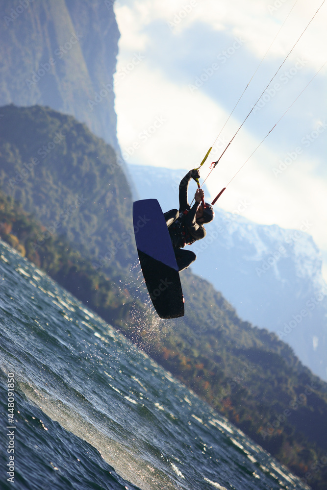 joven saldando en kite surf. con lago y montañas joven saldando en kite surf. con lago y montañas