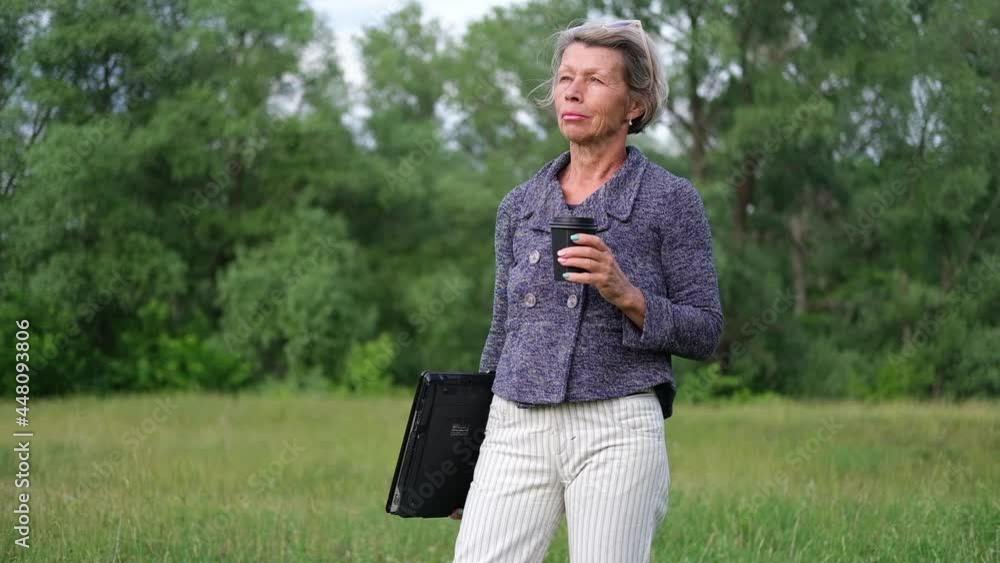  senior business woman with laptop, while dink coffee
