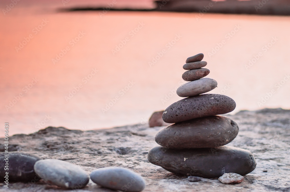 Fototapeta premium Pyramid stones balance on the sand of the beach. The object is in focus,sunset view.