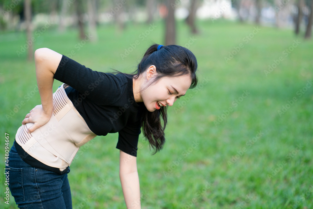 young asian woman wearing back support for protect her back, medicine and healthy concept