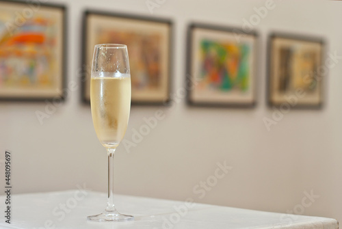 Glasses with wine on the background of the exhibition of paintings. Artwork blurred in the background. Art salon with white walls.
