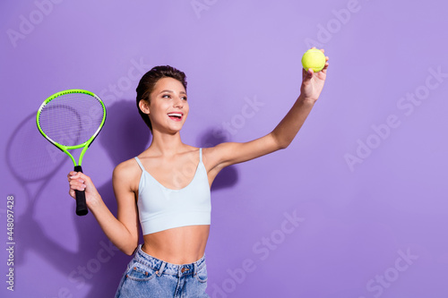 Photo portrait girl smiling keeping racket playing tennis with ball isolated pastel violet color background © deagreez