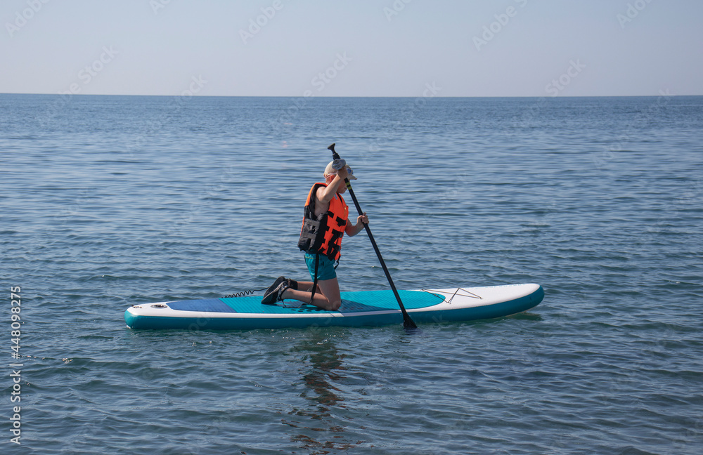 Naklejka premium boy sailing on Sup board on the sea
