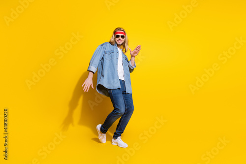 Photo of sweet funny young gentleman wear jeans shirt dark glasses dancing smiling isolated yellow color background