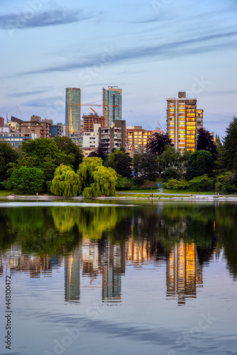 View of Lost Lagoon in famous Stanley Park in a modern city with buildings skyline in background. Colorful Sunset Sky. Downtown Vancouver  British Columbia  Canada.