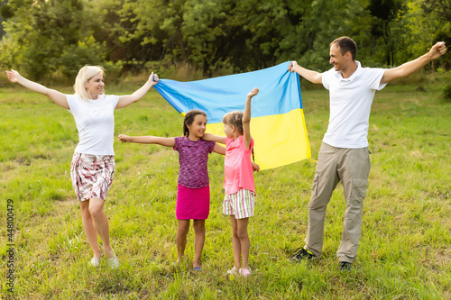 Flag Ukraine in hands of little girl in field. Child carries fluttering blue and yellow flag of Ukraine against background field. © Angelov
