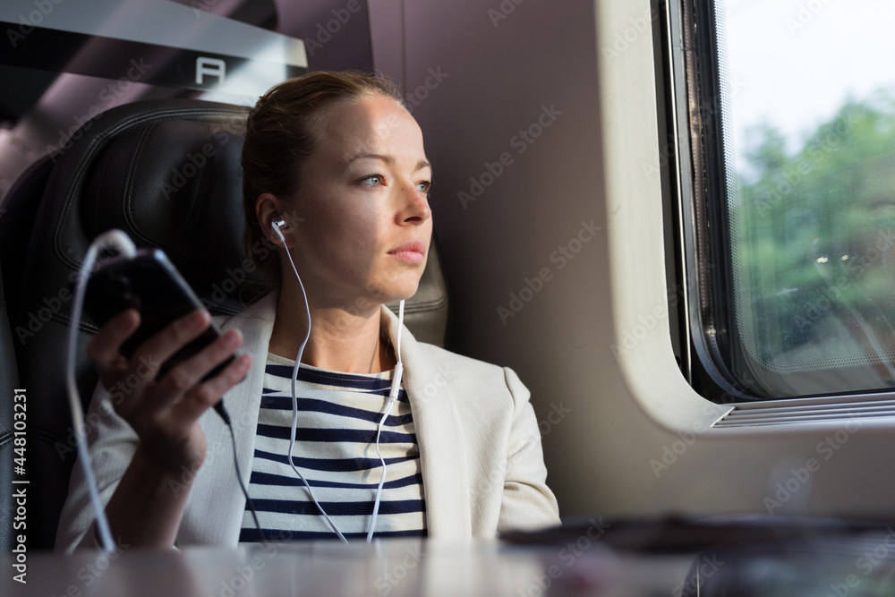 Businesswoman communicating on mobile phone while traveling by train. Businesswoman communicating on mobile phone while traveling by train.