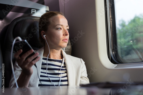 Businesswoman communicating on mobile phone while traveling by train. © kasto
