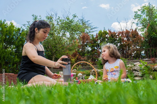 little girl and her sister are playing games and having a picnic in the garden