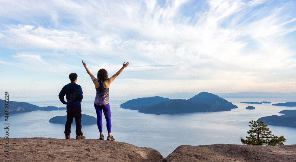 Obraz premium Adventurous Adult Man and Woman hiking on top of a mountain during a colorful sunny summer day. Hands Up. Tunnel Bluffs Hike, North of Vancouver, BC, Canada.