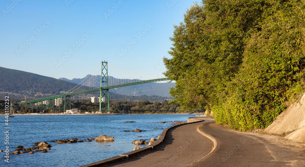 View of the Famous Lions Gate Bridge from Seawall at Stanley Park in a modern city. Downtown Vancouver, British Columbia, Canada. Sunny Summer Sunset.