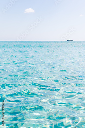 July 23, 2021: Boat sails in the crystal clear waters near La Cinta beach in Sardinia, Italy