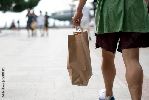 person carrying the paper bag with fresh food from the grocery store