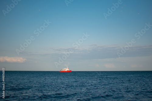 Sea overview with amazing blue sky and red ship sailing
