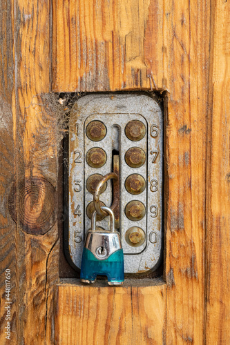 An old rusty closed lock on a weathered wooden door with cracks