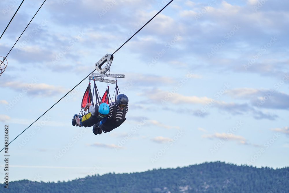 Unrecognizable people on zip line over mountains Unrecognizable people on zip line over mountains