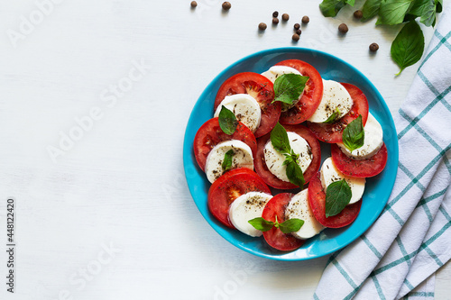 traditional Italian caprese salad. sliced red tomatoes, mozzarella cheese, green basil, olive oil on a white background. fresh salad with copy space. top view.flat lay