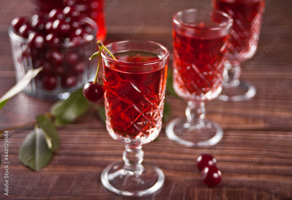 glasses of cherry brandy liqueur with ripe berries on wooden table glasses of cherry brandy liqueur with ripe berries on wooden table