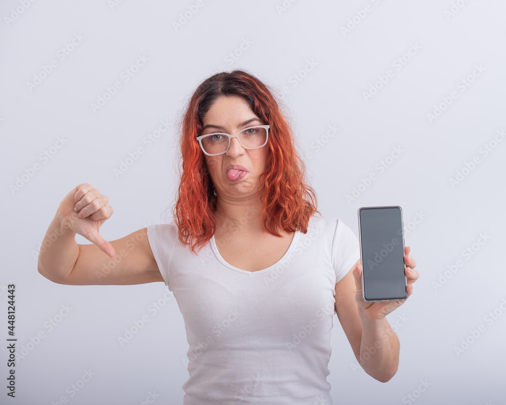 Caucasian woman holding smartphone with black screen and showing thumb down.