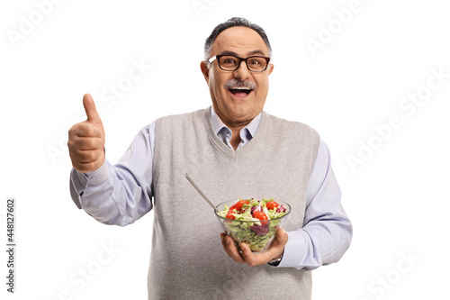 Cheerful mature man holding a healthy fresh salad in a bowl and showing thumbs up