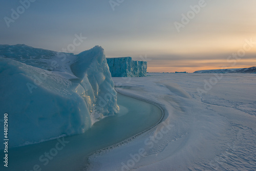 Ice berg on frozen sea at sunrise