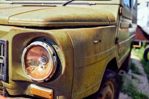 Fragment of the front of an old rusty car with a broken headlight
