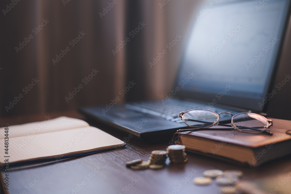 investment concept, glasses, bookand laptop on brown, black,  background. Business, investment, income concept, vintage style