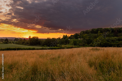 Colorful sunset on a warm summer evening over the rolling hills in Limburg. The sky showed amazing colours which gives a natural contrast to the green colours of the forest and meadow