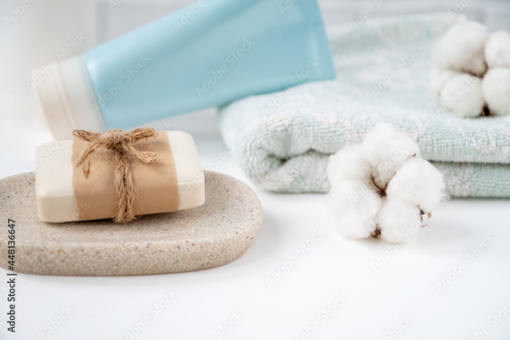 Bathroom table with new soap bar on tray, fresh clean towel and tube of cosmetics onit decorated with fluffy cotton balls. Bathroom table with new soap bar on tray, fresh clean towel and tube of cosmetics onit decorated with fluffy cotton balls.