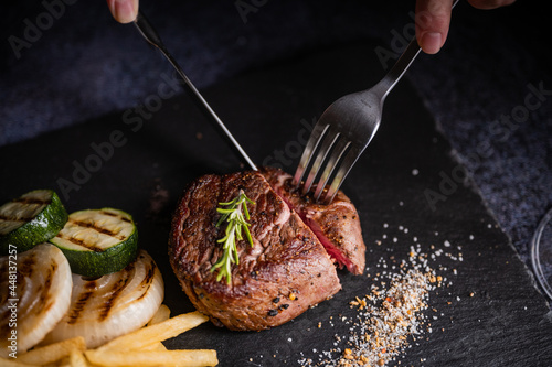 cutting tenderloin beef steak with knife and fork