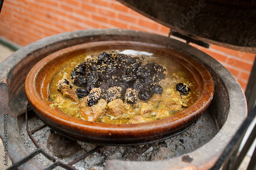 photo of meat with prunes cooked in a tagine on coals.Traditional Moroccan cuisine