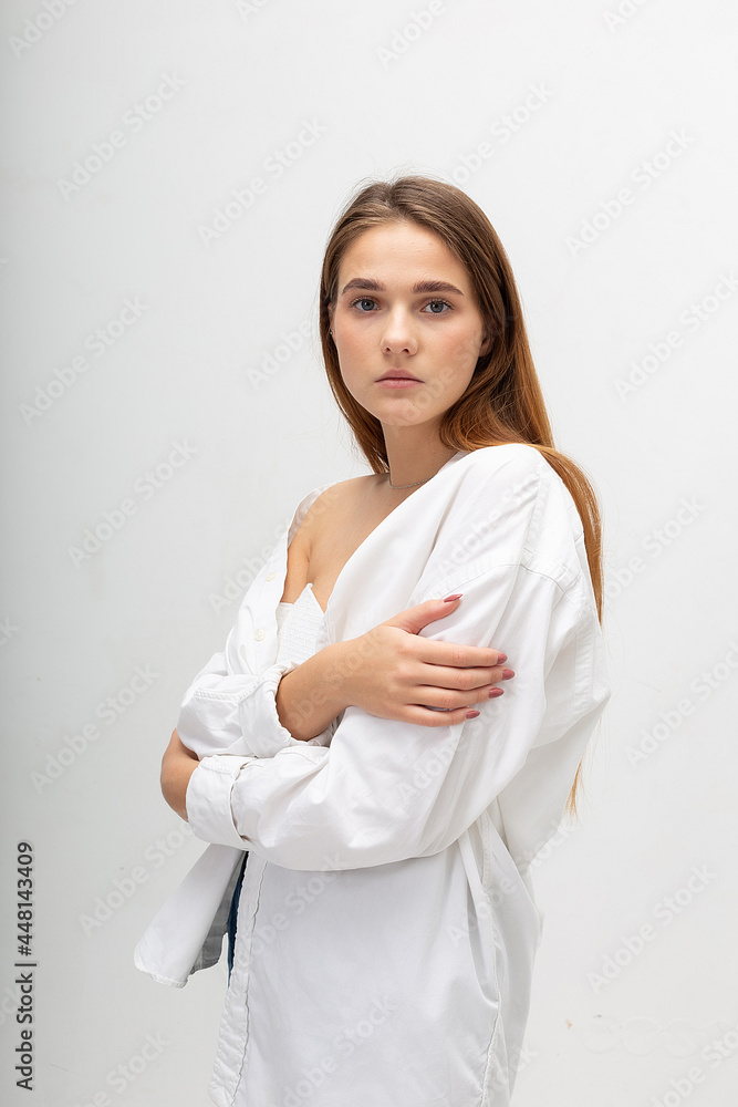 young attractive caucasian woman with long brown hair in shirt, blue jeans on white studio background. skinny pretty lady posing at bright room. portrait of beautiful female young attractive caucasian woman with long brown hair in shirt, blue jeans on white studio background. skinny pretty lady posing at bright room. portrait of beautiful female