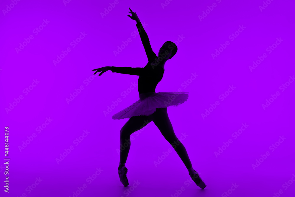 Professional ballet dancer on purple studio wall with violet light. Sensual ballerina dancing. Beautiful silhouette of woman in tutu dress. Solo performance.