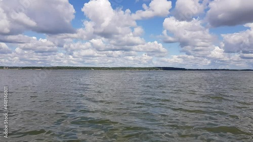 Motor boat trip along the waves of the picturesque Senezh lake. Skyline, green trees on the shore and cloudy blue sky on a sunny day. Moscow region, Russia
